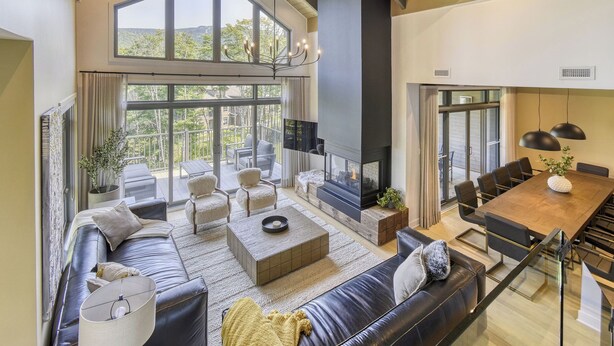 A spacious living area with a fireplace, large windows, and a dining area. - 201 Verbier Building 7 (Mont-Tremblant)