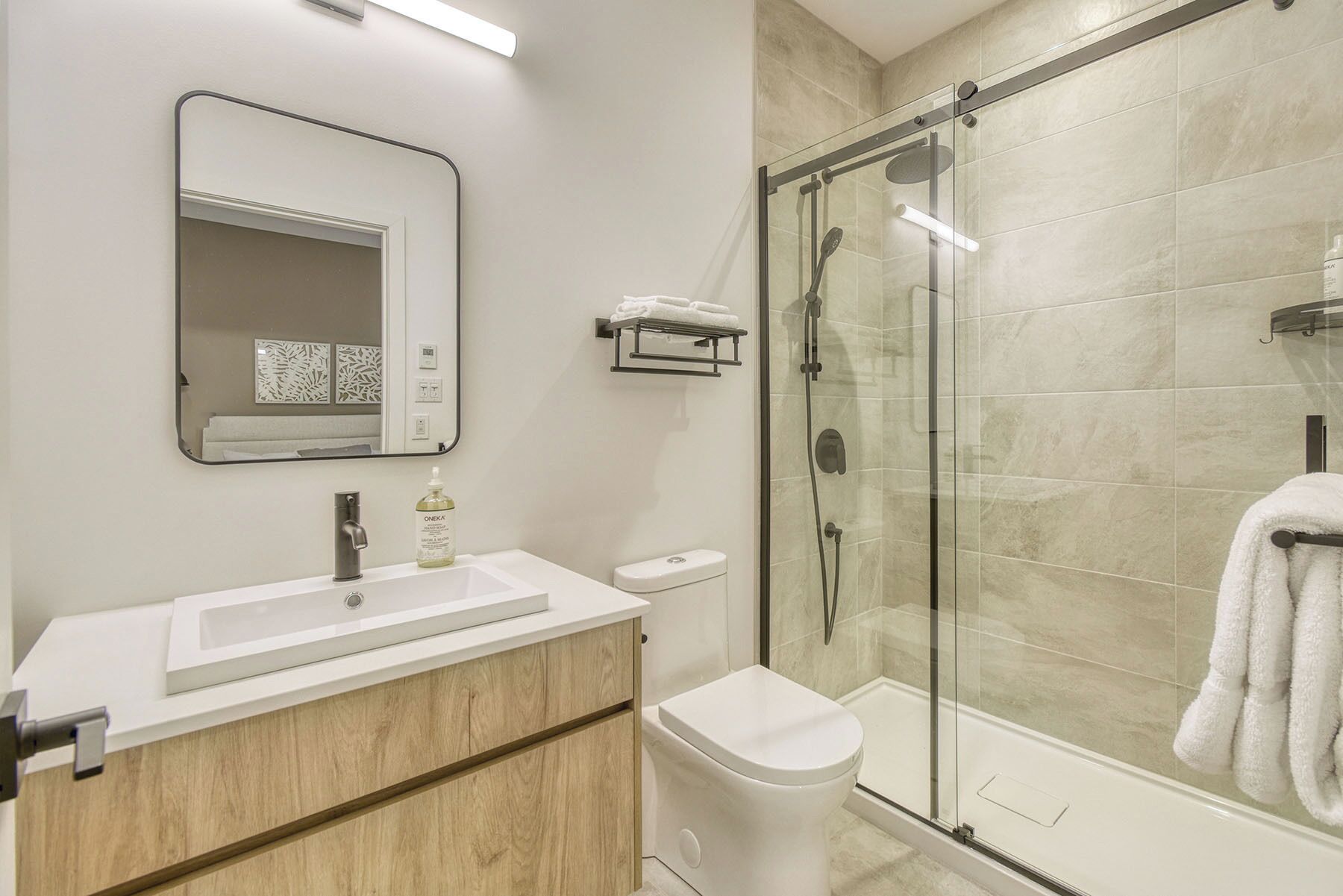 A modern bathroom with a glass-enclosed shower, a white sink, and a toilet.