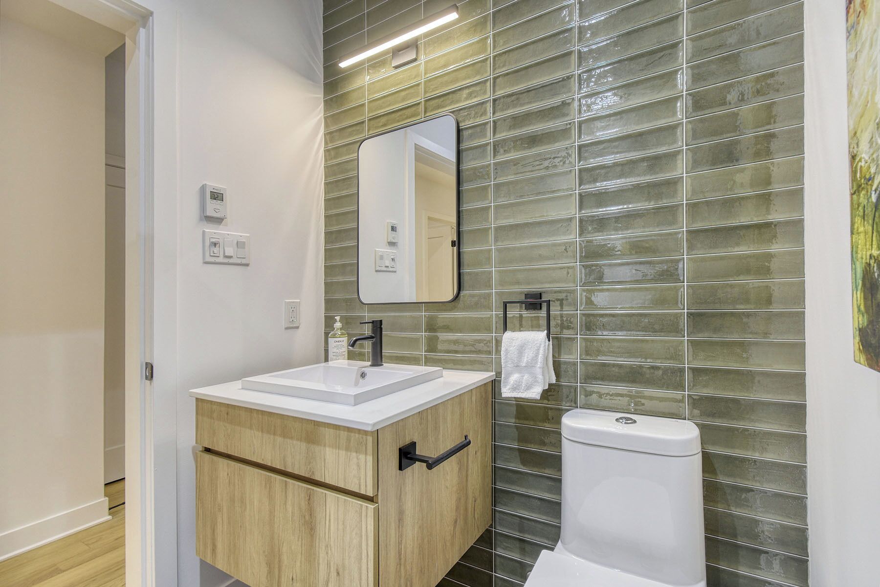 A modern bathroom with a wooden vanity, a white sink, and a toilet.