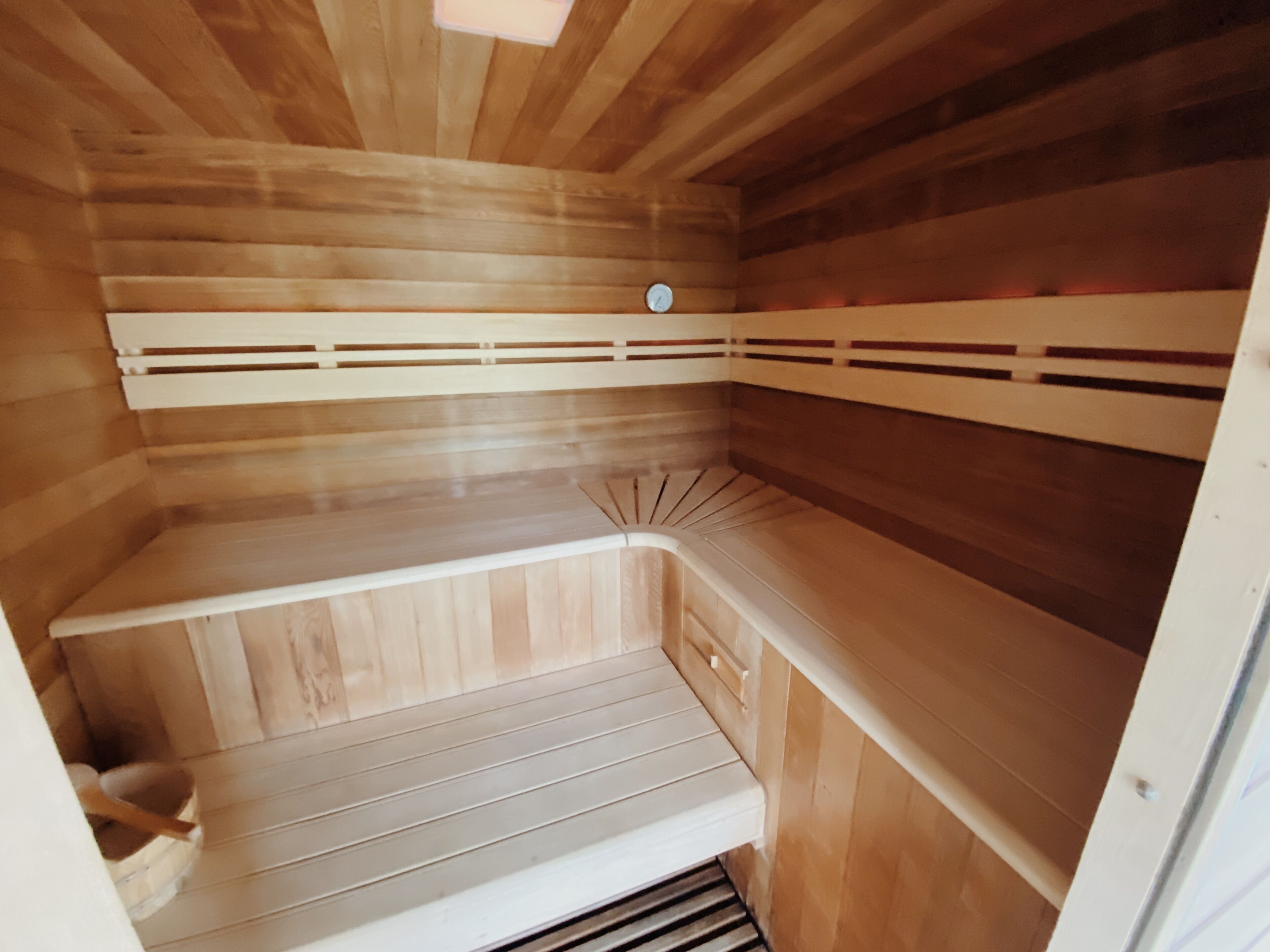 A sauna with wooden benches and a sloped floor.