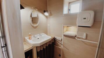 Une petite salle de bain comprenant un lavabo, un miroir, un porte-serviettes et une petite fenêtre.