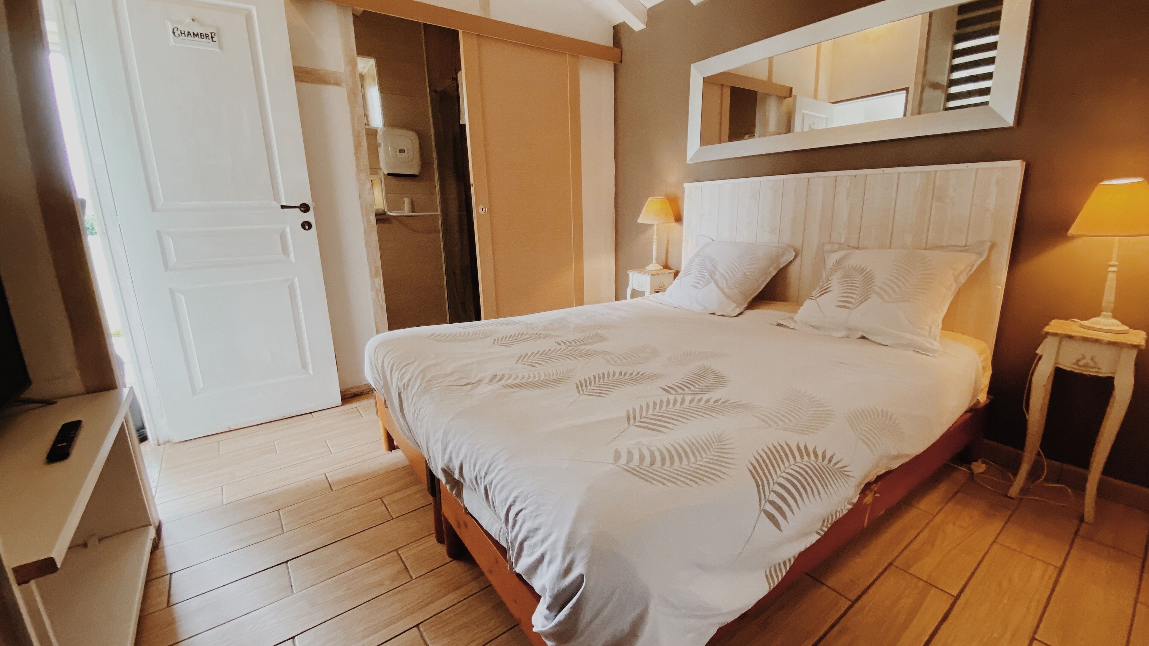 Ein Schlafzimmer mit Bett, Nachttisch, Spiegel und Tür.