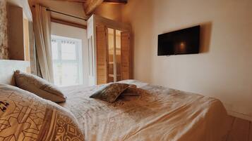 A bedroom with a bed, a TV, and a window with curtains.