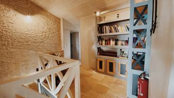 A wooden staircase leading to a room with a stone wall, a bookshelf, and a fire extinguisher.