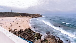 Une plage avec des affleurements rocheux et des vagues qui déferlent sur le rivage.