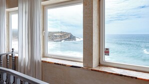 Une pièce avec vue sur l’océan grâce à de grandes fenêtres, un escalier et un panneau « Alarme » bien visible.