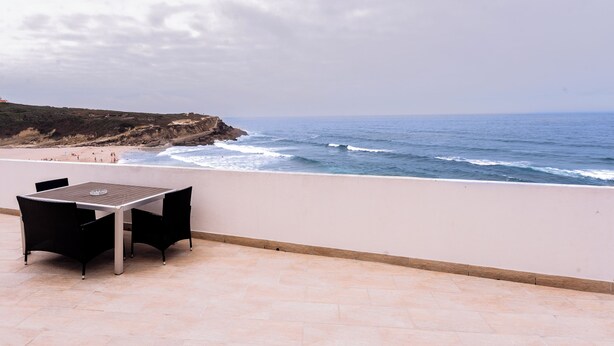 Une terrasse avec une table et des chaises donnant sur l’océan.