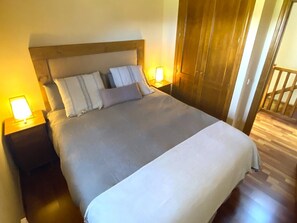 A bedroom with a large bed, wooden headboard, two bedside tables with lamps, and a wooden floor. - Townhouse 3 rooms Pool, Fireplace, Garden & Dryer (Palau-de-Cerdagne)