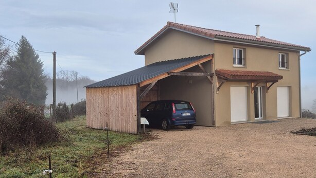 Une maison à deux étages avec un garage, une voiture garée à l’intérieur et une allée gravillonnée.