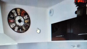 Une cuisine équipée d’une horloge, de placards, d’un évier et d’un plan de travail.