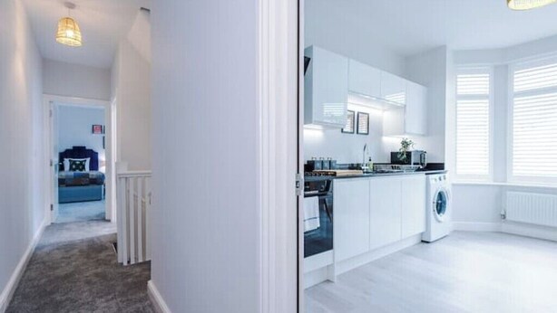 A modern kitchen with white cabinetry, a built-in oven, and a washing machine. - Parkview Place by Patternbricks (Coventry)