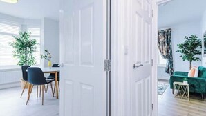 A room with a dining area, a green sofa, and a door leading to another room. - Parkview Place by Patternbricks (Coventry)