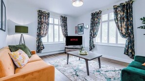 A living room with a sofa, a coffee table, a TV, and curtains. - Parkview Place by Patternbricks (Coventry)
