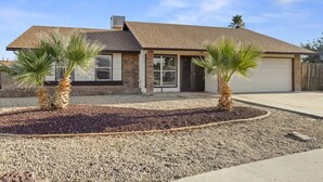 A single-story house with a brick exterior, a garage, and two palm trees in the front yard. - Large Pool, Near State Farm STDM and Many Entertainment Districts! (Peoria)