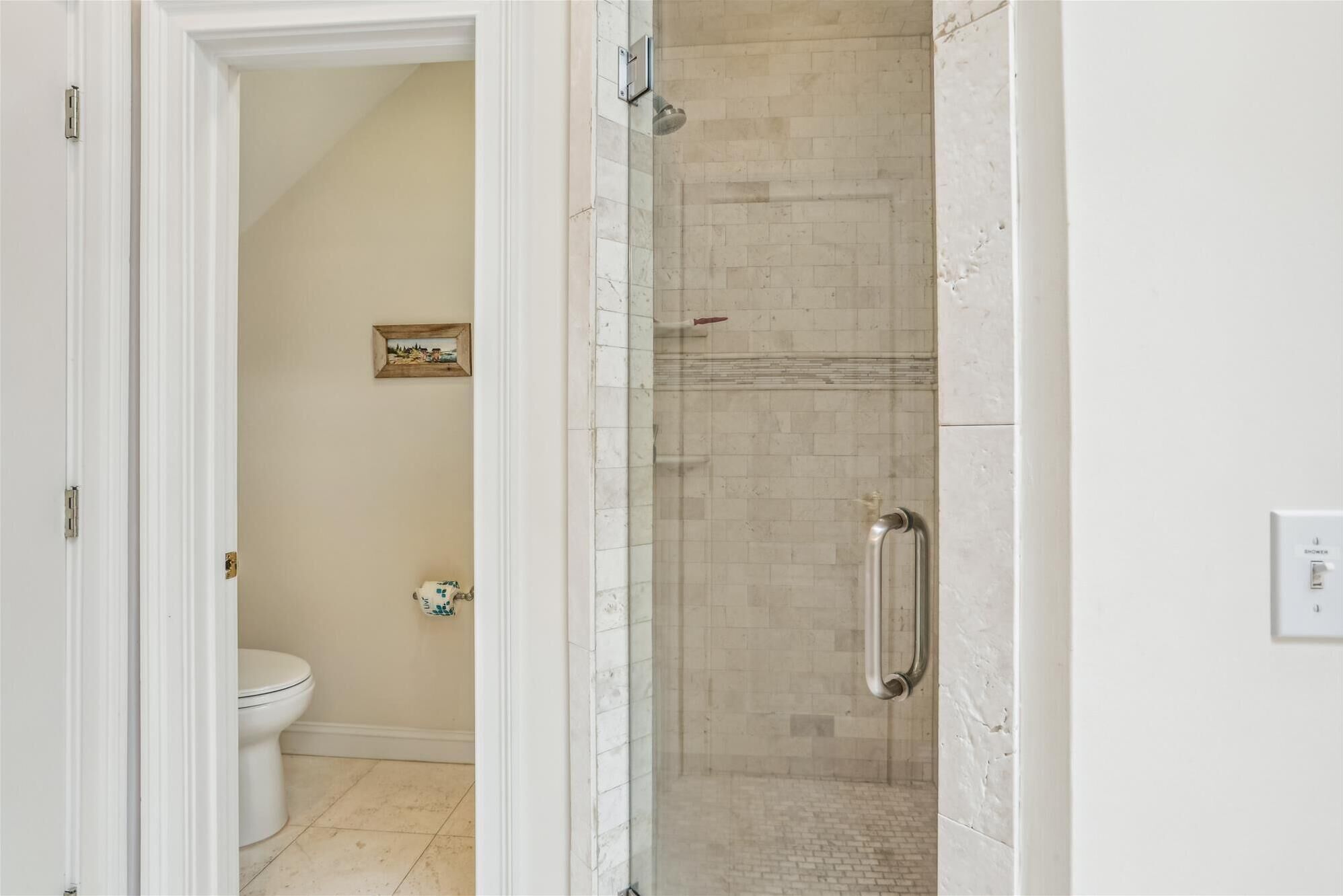 A bathroom with a shower, toilet, and a small decorative item on the wall.