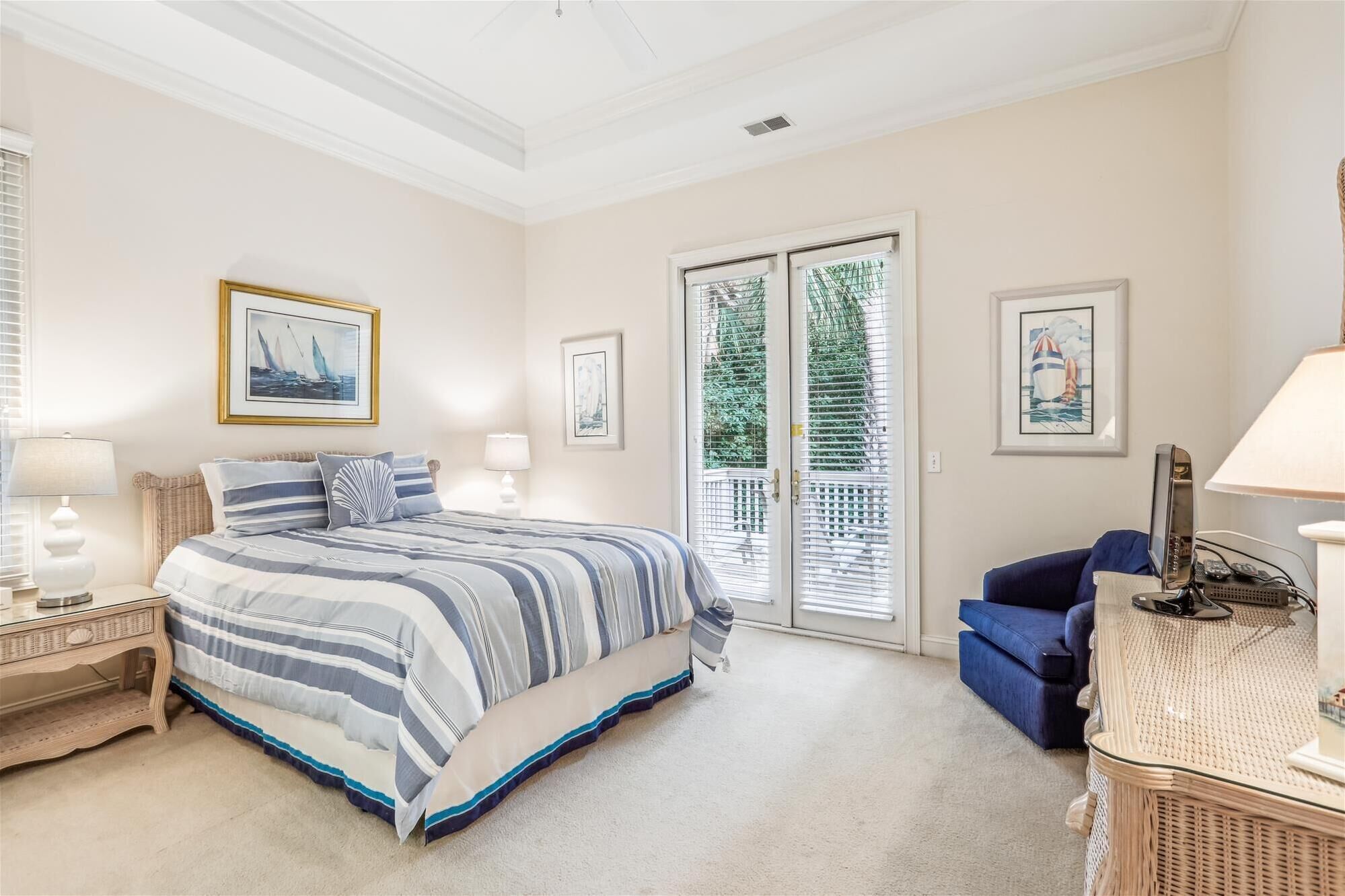 A bedroom with a large bed, two bedside tables with lamps, a blue sofa, and a wicker side table.