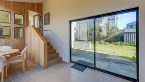Een modern interieur met een houten trap, een eethoek en een grote schuifdeur die uitkomt op een achtertuin.