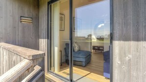 Fachada de madeira com porta de vidro deslizante que dá para um quarto com sofá azul e uma pequena mesa.
