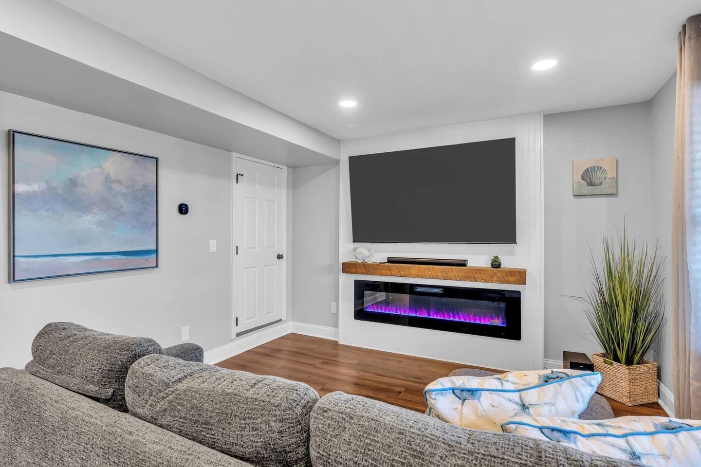Una sala de estar moderna con un televisor de pantalla plana, una chimenea y un cuadro grande en la pared.