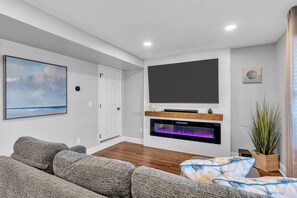 A modern living room with a flat-screen TV, a fireplace, and a large painting on the wall.