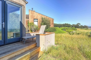 A modern house with a wooden deck, a glass door, and a chair.