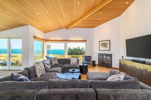 A modern living room with a large gray sectional sofa, a fireplace, and a television.