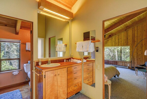A wooden cabin-style bathroom with a large mirror, wooden cabinets, and a sink.
