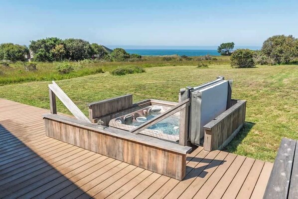 Un jacuzzi en una terraza de madera con vista al océano.