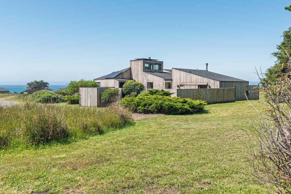 Une maison moderne dotée d’une grande pelouse et offrant une vue sur l’océan.