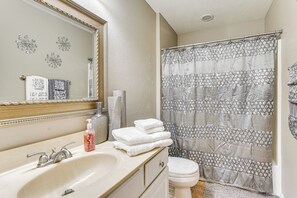 Un baño con lavamanos, espejo y cortina de ducha.