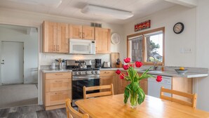 Une cuisine moderne avec des meubles en bois, un four à micro-ondes, une cuisinière et une table à manger avec des chaises.