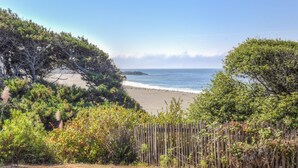 Une plage avec une clôture en bois au premier plan et une vue dégagée sur l’océan.