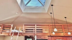 Una cocina moderna con armarios de madera, tragaluces y lámparas colgantes.