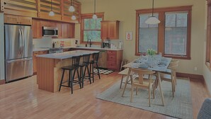 Una cocina moderna con armarios de madera, electrodomésticos de acero inoxidable y una isla central con taburetes de bar.