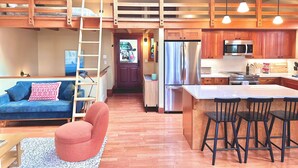 Una cocina compacta con una isla central, armarios de madera y un refrigerador de acero inoxidable.