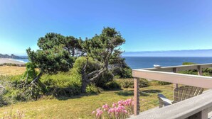 A coastal property with a view of the ocean, a wooden deck, and a grassy area with pink flowers. - Lucky Ewe - Gualala | 3BR | Ocean Views | Sleeps 6 (Gualala)