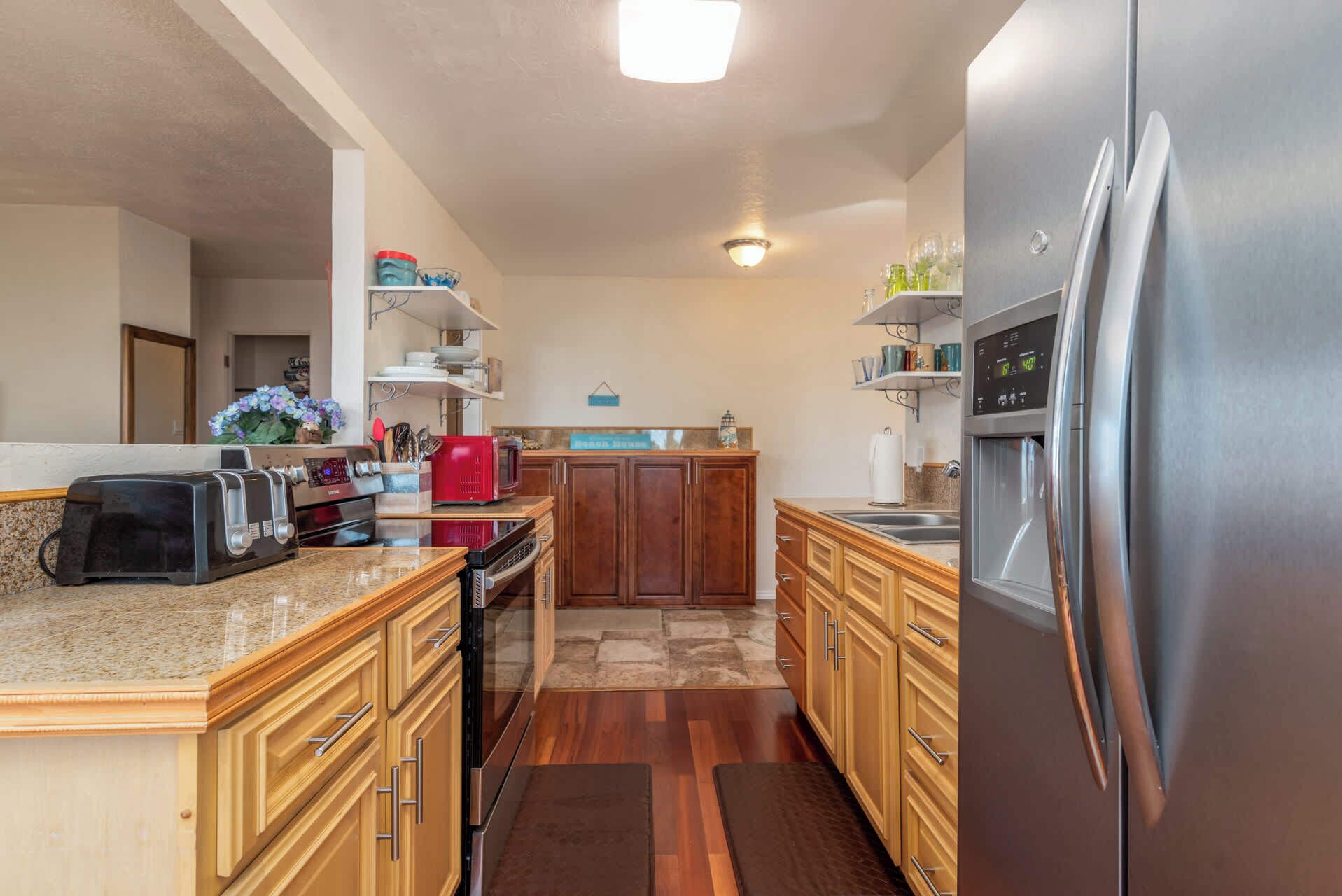 A modern kitchen with wooden cabinets, stainless steel appliances, and a granite countertop.