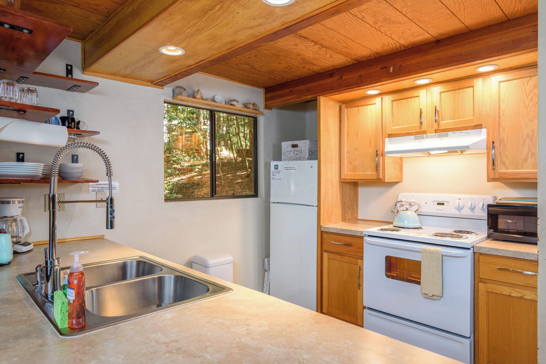 Une cuisine avec des meubles de rangement en bois, un évier en acier inoxydable, un réfrigérateur blanc et une cuisinière.