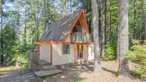 Een chalet met schuin dak, een balkon en een houten terras.