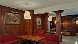 Interior de madera con una mesa y bancos de madera, un cuadro en la pared y un letrero que indica la salida.