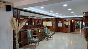 Un vestíbulo con mostrador de recepción, dos sillas, una lámpara y una escalera.