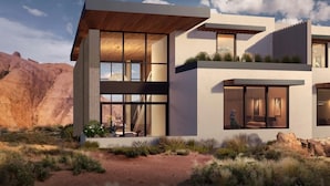 Una casa moderna con amplios ventanales, techo plano y paisaje desértico al fondo.
