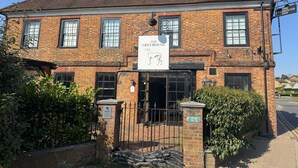 Un edificio tradicional de ladrillo con un letrero que dice 'The Greyhound Inn'.