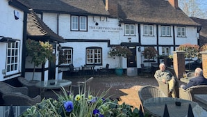 El Greyhound Inn, un edificio tradicional con fachada blanca y detalles negros, ofrece terraza y un letrero que indica que es hotel, bar y restaurante.