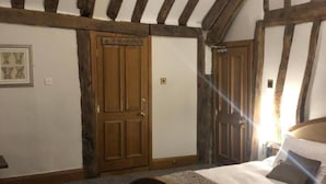 Un dormitorio con una cama grande, vigas de madera en el techo y una puerta con diseño de paneles.