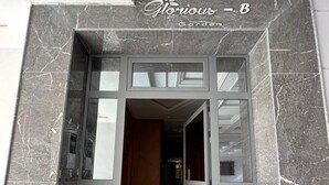 Une entrée moderne avec une porte en verre et une façade en marbre.