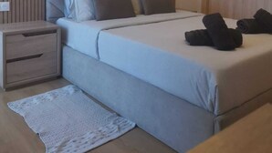 Une chambre à coucher moderne, comprenant un lit, des tables de chevet, une commode, un luminaire fixé au mur et une porte.