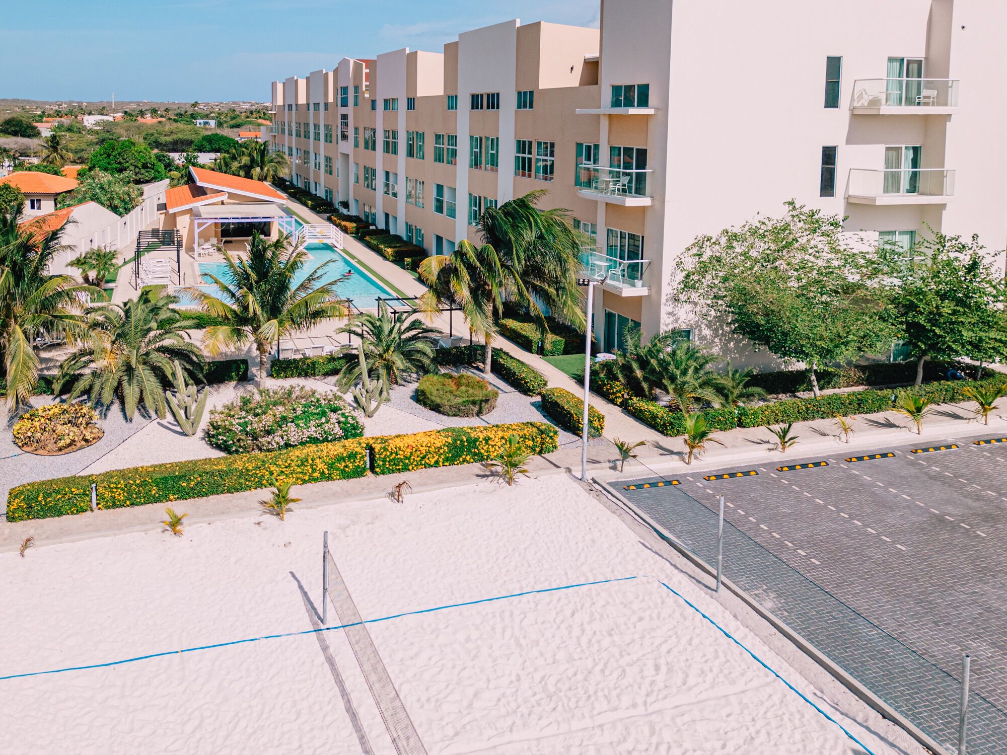 A modern hotel with multiple floors, a swimming pool, and landscaped gardens.