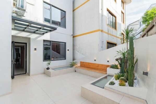 A modern courtyard with a glass water feature, a wooden bench, and various plants. - Banyue Yuge Guesthouse (Wenzhou)