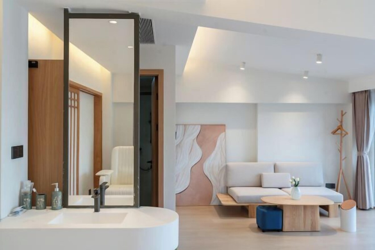 A modern bathroom with a large mirror, a sink, and a toilet.